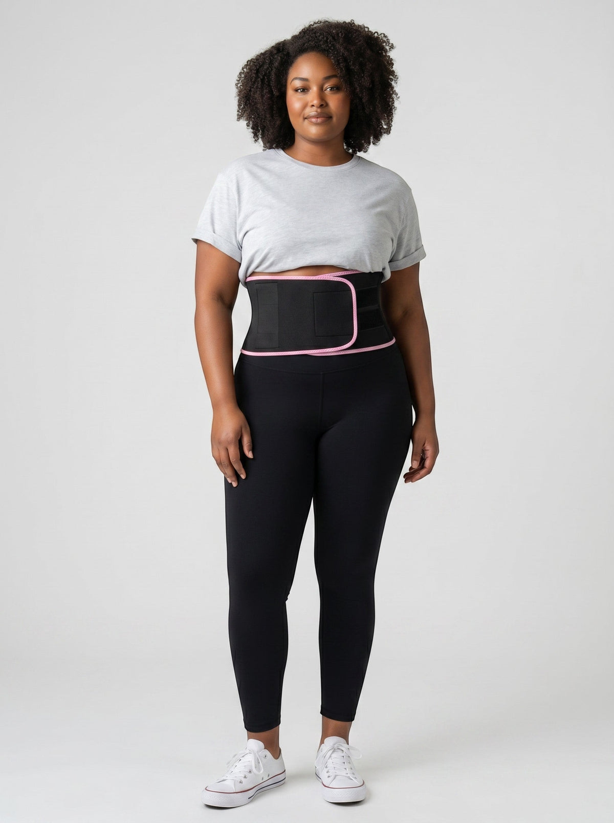 Woman wearing a black ThermoCore waist trimmer with pink trim over black leggings and a grey t-shirt