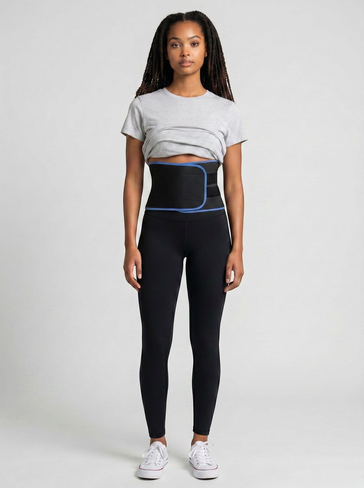 Woman wearing a black ThermoCore waist trimmer belt with blue trim over black leggings and a grey t-shirt