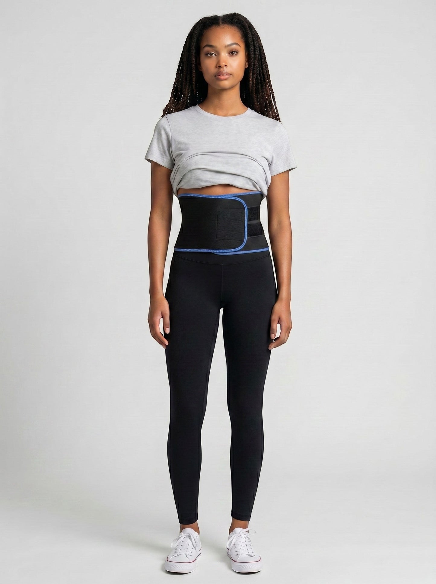 Woman wearing a black ThermoCore waist trimmer belt with blue trim over black leggings and a grey t-shirt